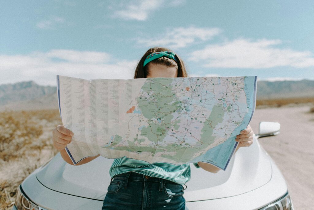 Woman leaning against a car looking at a map