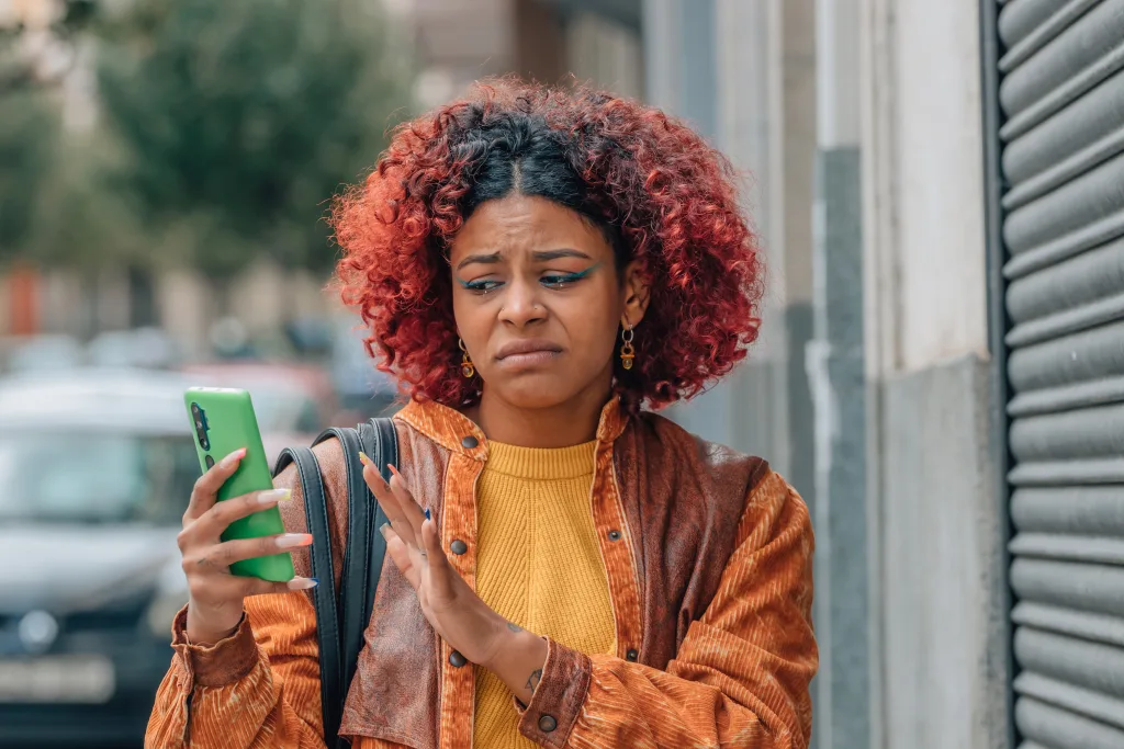 Woman looking at cell phone with disgusted expression on her face