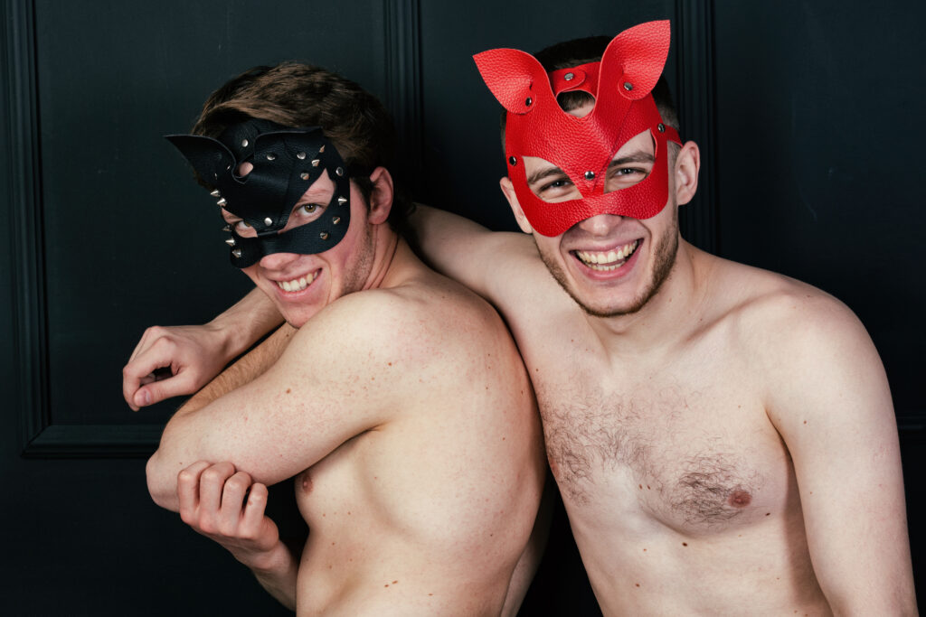 Two men smiling while wearing fetish masks