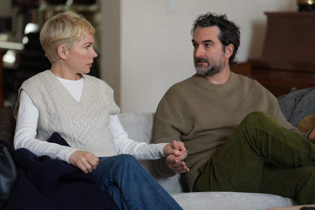 A woman and man sitting next to each other on a couch, holding hands and looking at each other intensely