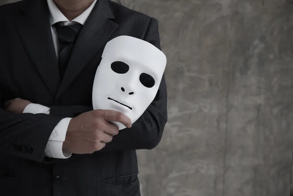 Man in a suit holding a mask