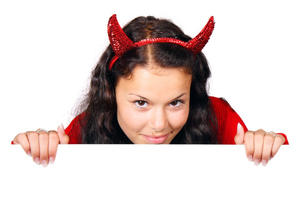 woman with mischievous smile wearing devil horns headband