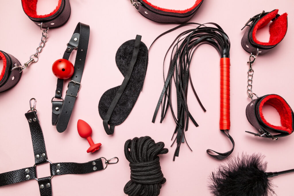 A group of BDSM toys, including rope, a blindfold, and a flogger