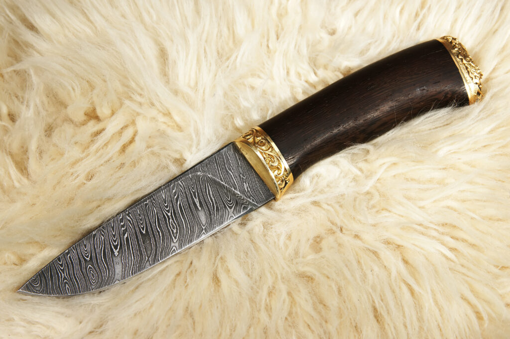 Knife with damascus steel blade resting on sheepskin.