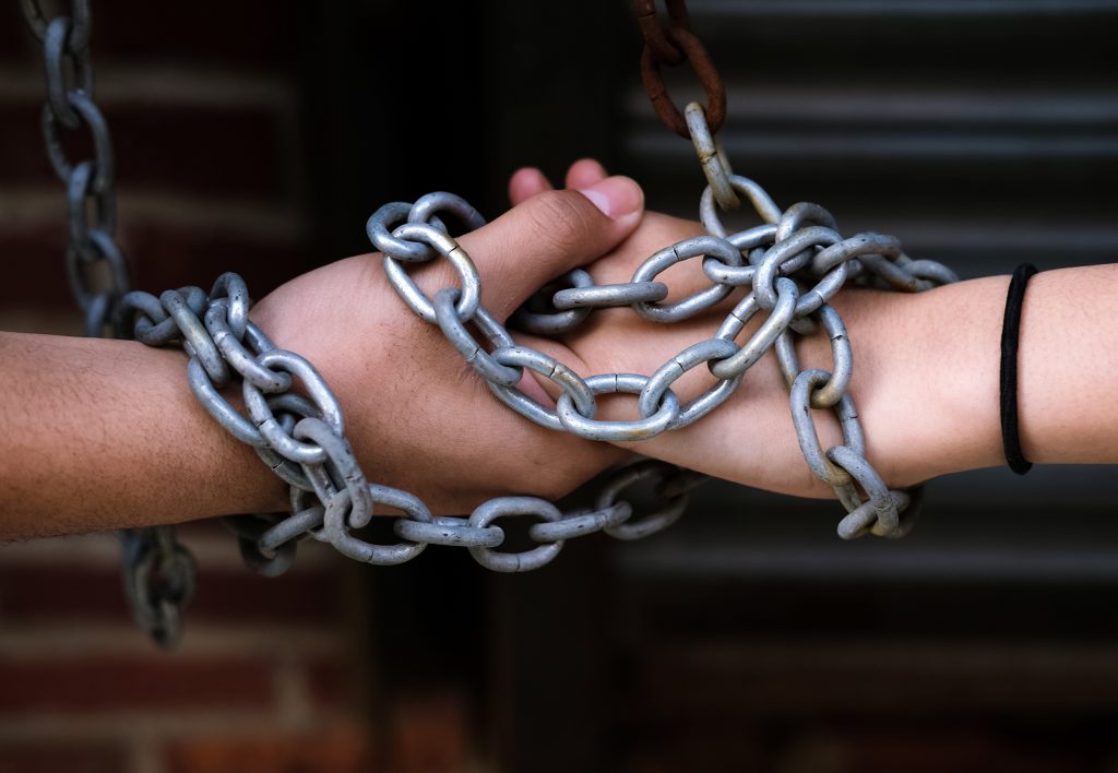 Close-up of two hands wrapped together in chains