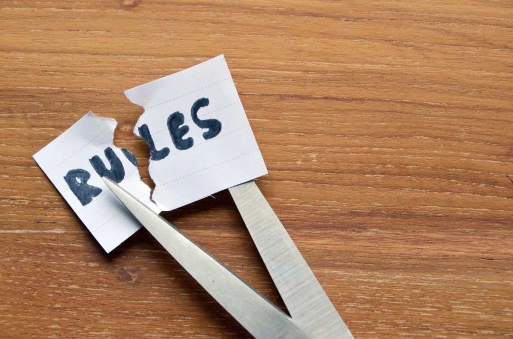 Scissors cutting a piece of paper with the word RULES on it