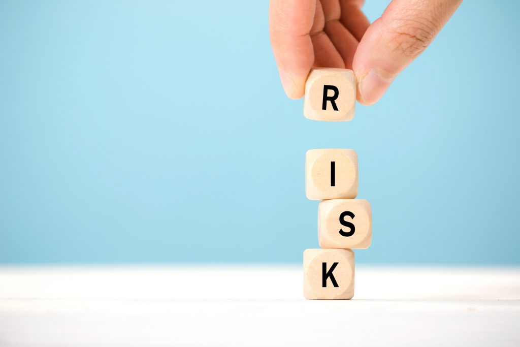 Wooden blocks stacked on top of each other spelling the word "Risk"