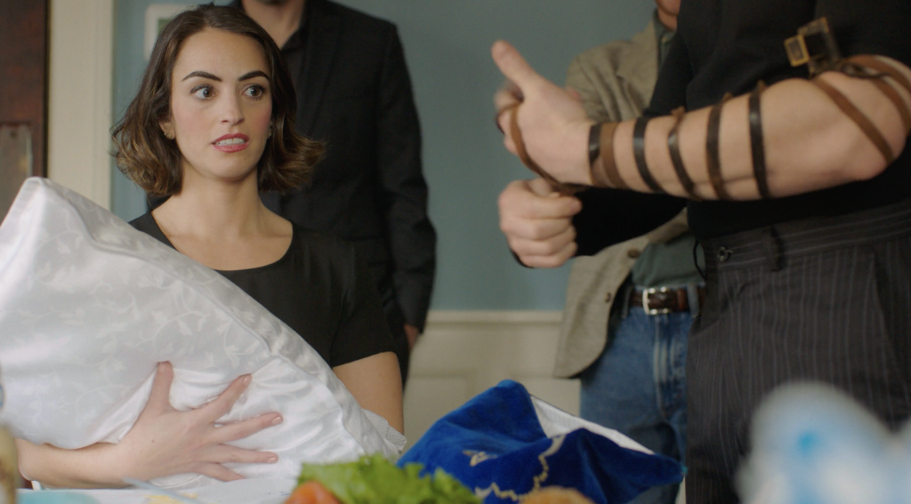 A woman staring intently at a man wrapping tefillin. From the 2022 short film Good Girl.