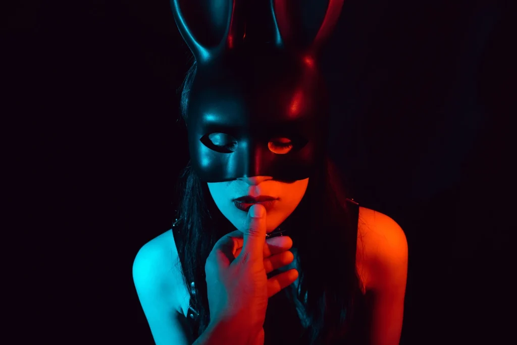 Woman wearing black mask with someone touching her mouth