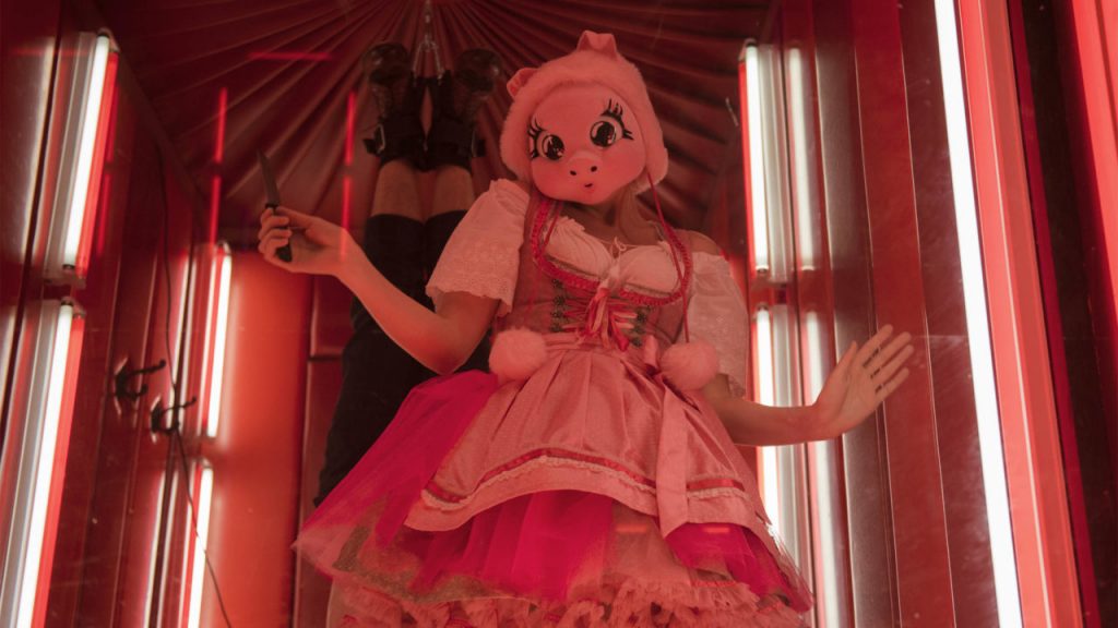 Scene from season 2 of Killing Eve; woman in flouncy dress wearing a pig mask and holding a knife