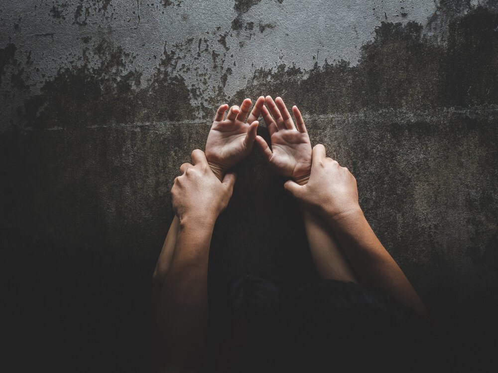 Man's arms pinning woman's arms to a wall